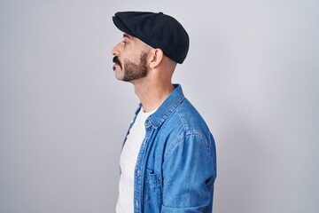 Hispanic man with beard standing over isolated background looking to side, relax profile pose with natural face and confident smile.