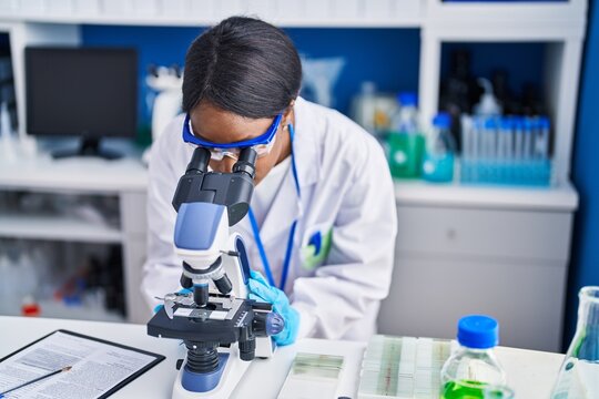 Young african american woman scientist using microscope at laboratory