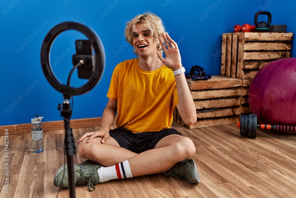 Sticker young man recording training tutorial at the gym looking positive and happy standing and smiling wit