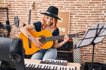 Young caucasian woman musician playing classical guitar at music studio