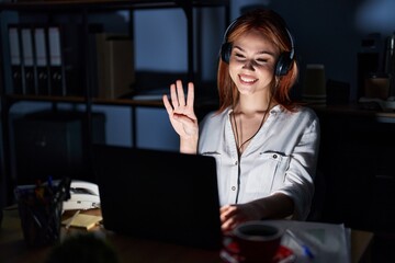 Young caucasian woman working at the office at night showing and pointing up with fingers number...