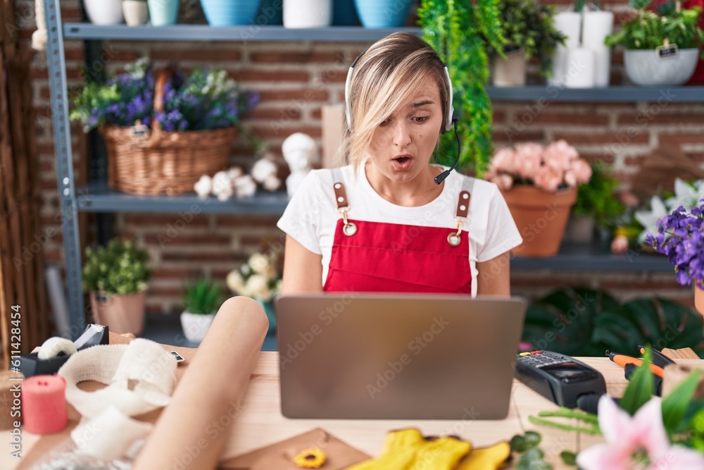 Sticker Young blonde woman working at florist shop doing video call scared and amazed with open mouth for surprise, disbelief face