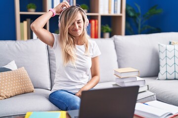 Young blonde woman studying using computer laptop at home confuse and wondering about question....
