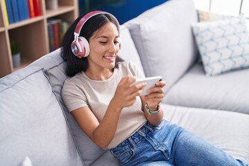 Young beautiful hispanic woman playing video game sitting on sofa at home © Krakenimages.com