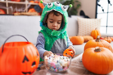 Adorable hispanic boy having halloween party holding sweets at home