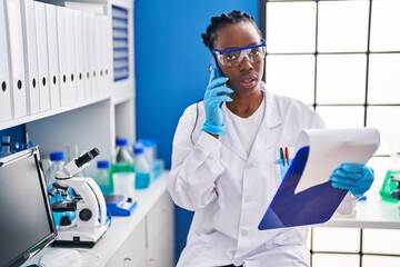 African american woman scientist reading document at laboratory