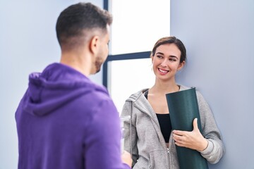 Man and woman hoilding yoga mat and bottle of water standing at sport center