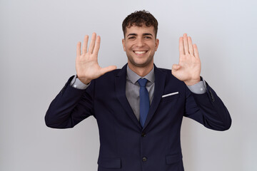Young hispanic business man wearing suit and tie showing and pointing up with fingers number nine while smiling confident and happy.