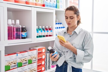 Young woman customer using smartphone holding medication bottle at pharmacy