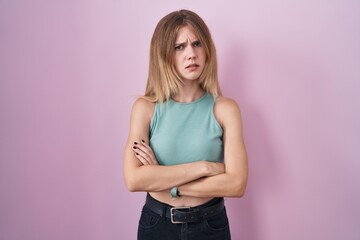 Blonde caucasian woman standing over pink background skeptic and nervous, disapproving expression...