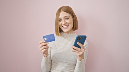 Young blonde woman shopping with smartphone and credit card over isolated pink background