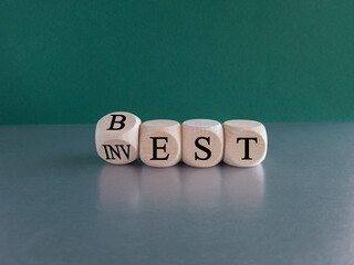 Best invest symbol. Turned a wooden cube and changes the word Invest to Best. Beautiful grey table, green background. Business and best invest concept. Copy space