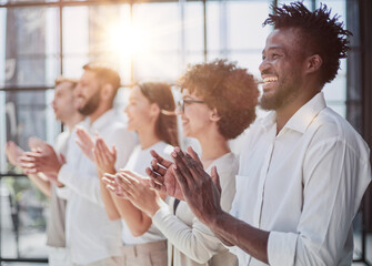 Group of businesspeople sitting in a line and applauding.