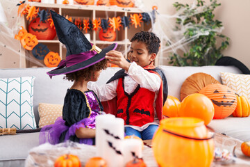 Fototapeta premium Adorable african american boy and girl wearing halloween costume sitting on sofa at home