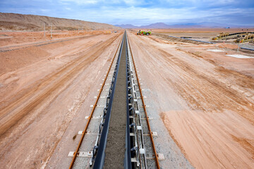 Minerals being transported on a long conveyor belt at a copper mine.