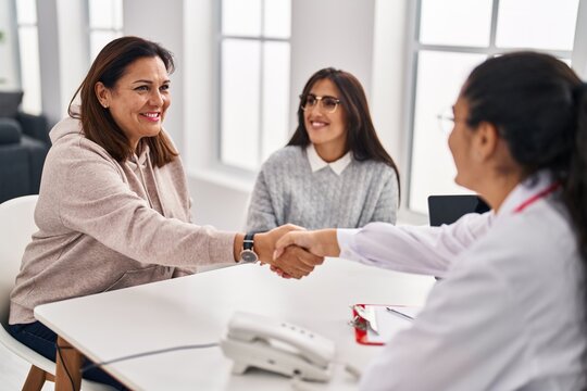 Three woman doctor and patients shake hands at clinic