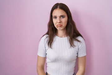 Fototapeta premium Young hispanic girl standing over pink background depressed and worry for distress, crying angry and afraid. sad expression.