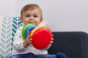 Naklejka premium Adorable caucasian boy playing with hoops game sitting on sofa at home