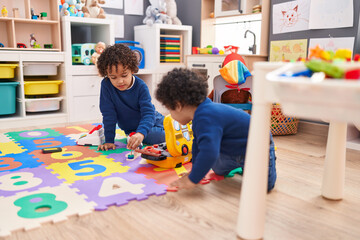 Adorable african american boys sitting on floor playing with tools at kindergarten