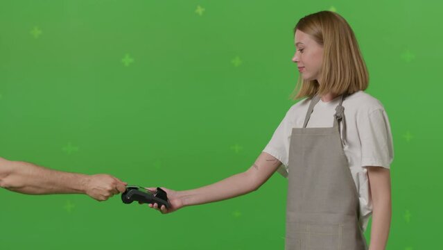 The waiter hands the package of food to the delivery man on green screen chroma key background. Woman hold wireless bank payment POS terminal to process acquire credit card payment