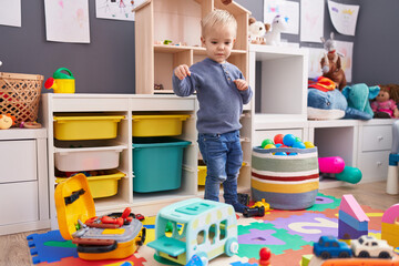 Adorable caucasian boy standing with relaxed expression playing at kindergarten