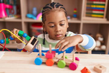 African american boy playing with blocks train toy sitting on table at kindergarten