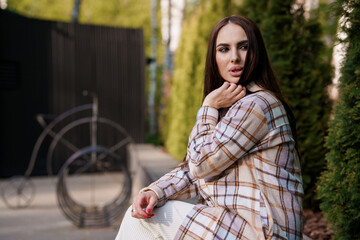 A girl in a plaid shirt sits on a bench. Portrait of a beautiful girl