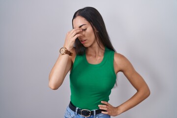 Young woman standing over isolated background tired rubbing nose and eyes feeling fatigue and...