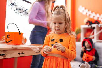 Fototapeta premium Adorable blonde girl wearing pumpkin costume holding sweet at home