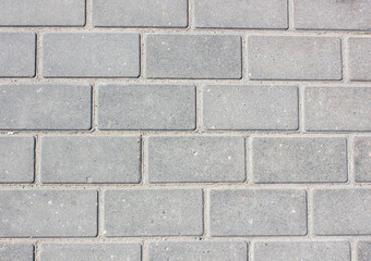 Brick paving slabs.Gray background of a brick pavement.Background of a block of gray stone tiles Surface of a gray brick.Stone pavement slab texture. Road,tile,concrete slab.