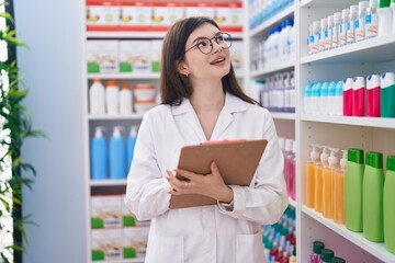 Young caucasian woman pharmacist writing on document at pharmacy