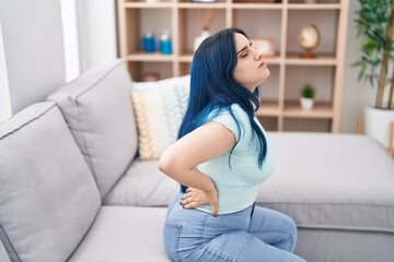 Young caucasian woman suffering for backache sitting on sofa at home