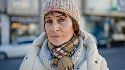 Mature hispanic woman standing with serious expression at street