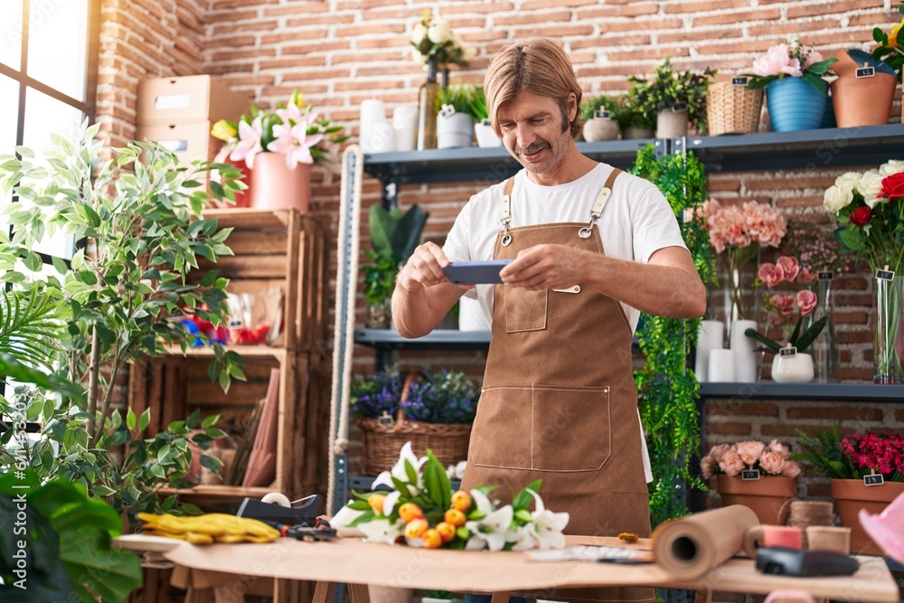 Canvas Prints Young blond man florist make photo to bouquet of flowers by smartphone at flower shop