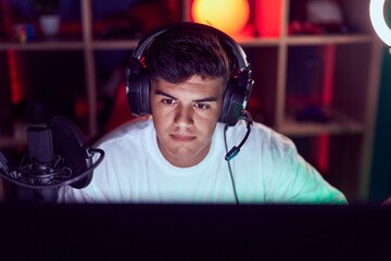 Young hispanic man streamer playing video game using computer at gaming room