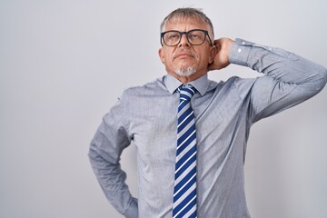 Hispanic business man with grey hair wearing glasses suffering of neck ache injury, touching neck with hand, muscular pain