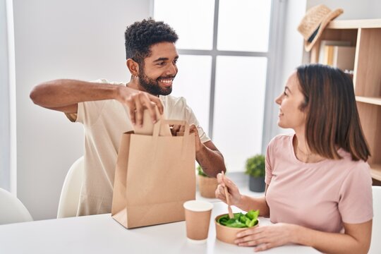 Man And Woman Couple Sitting On Table Eating Take Away Food At Home