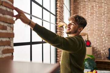 Young arab man smiling confident measuring window at new home