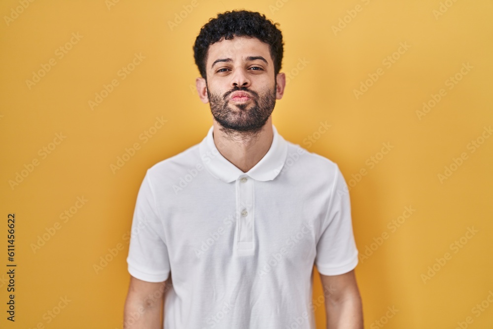 Poster arab man standing over yellow background looking at the camera blowing a kiss on air being lovely an