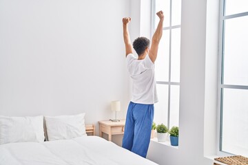 Young arab man waking up stretching arms at bedroom