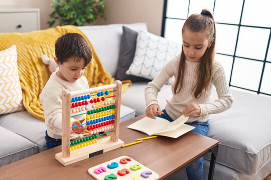 Adorable boy and girl playing with abacus drawing on notebook at home