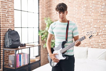 Young hispanic teenager musician playing electrical guitar at bedroom
