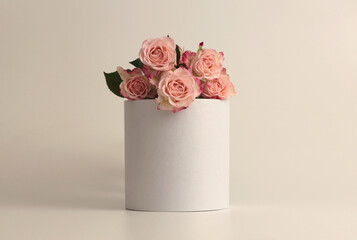 Pink rose flower bouquet on white podium. Light beige background. Minimal empty display product presentation scene.