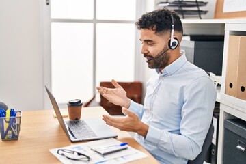 Young hispanic man call center agent having video call at office