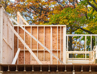 A residential construction project wall showing wall studs and sheathing with bracing on a floor supported by glue laminated joists