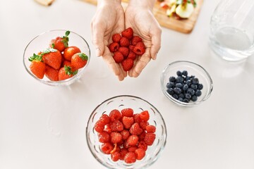 Young woman hoding raspberries at kitchen
