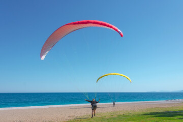 Two people paraglider are preparing to take off on a light breeze wind on the coast of the sea.
