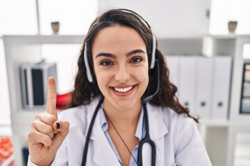 Young doctor woman working on online appointment smiling with an idea or question pointing finger with happy face, number one