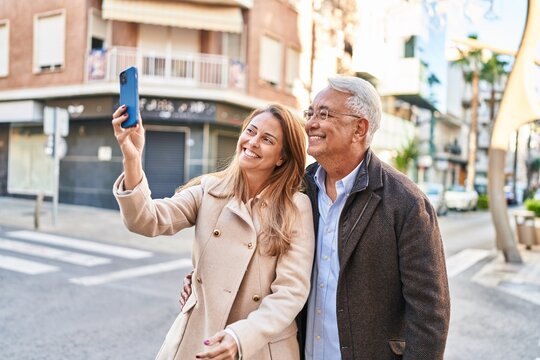 Middle age man and woman couple smiling confident making selfie by the smartphone at street