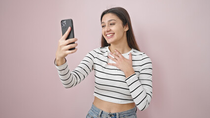 Naklejka premium Young beautiful hispanic woman smiling confident having video call over isolated pink background